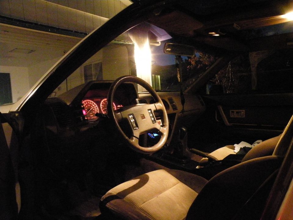 Interior of a Nissan 300ZX at night, showing illuminated dashboard and steering wheel.