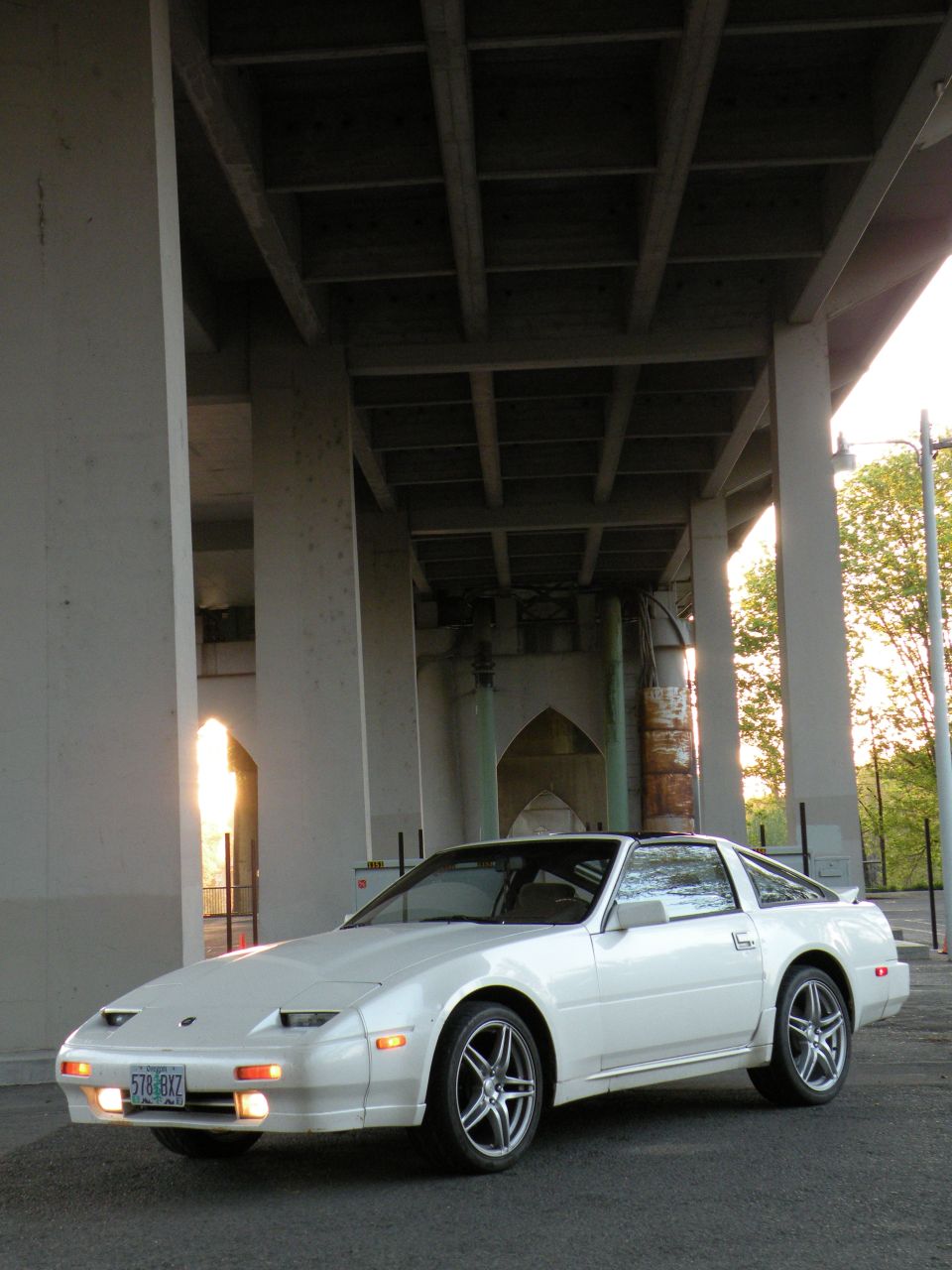 White 1989 Nissan 300ZX parked under a concrete overpass, front three-quarter view.