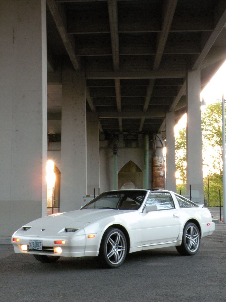 White 1989 Nissan 300ZX parked under a concrete overpass, front 3/4 view.