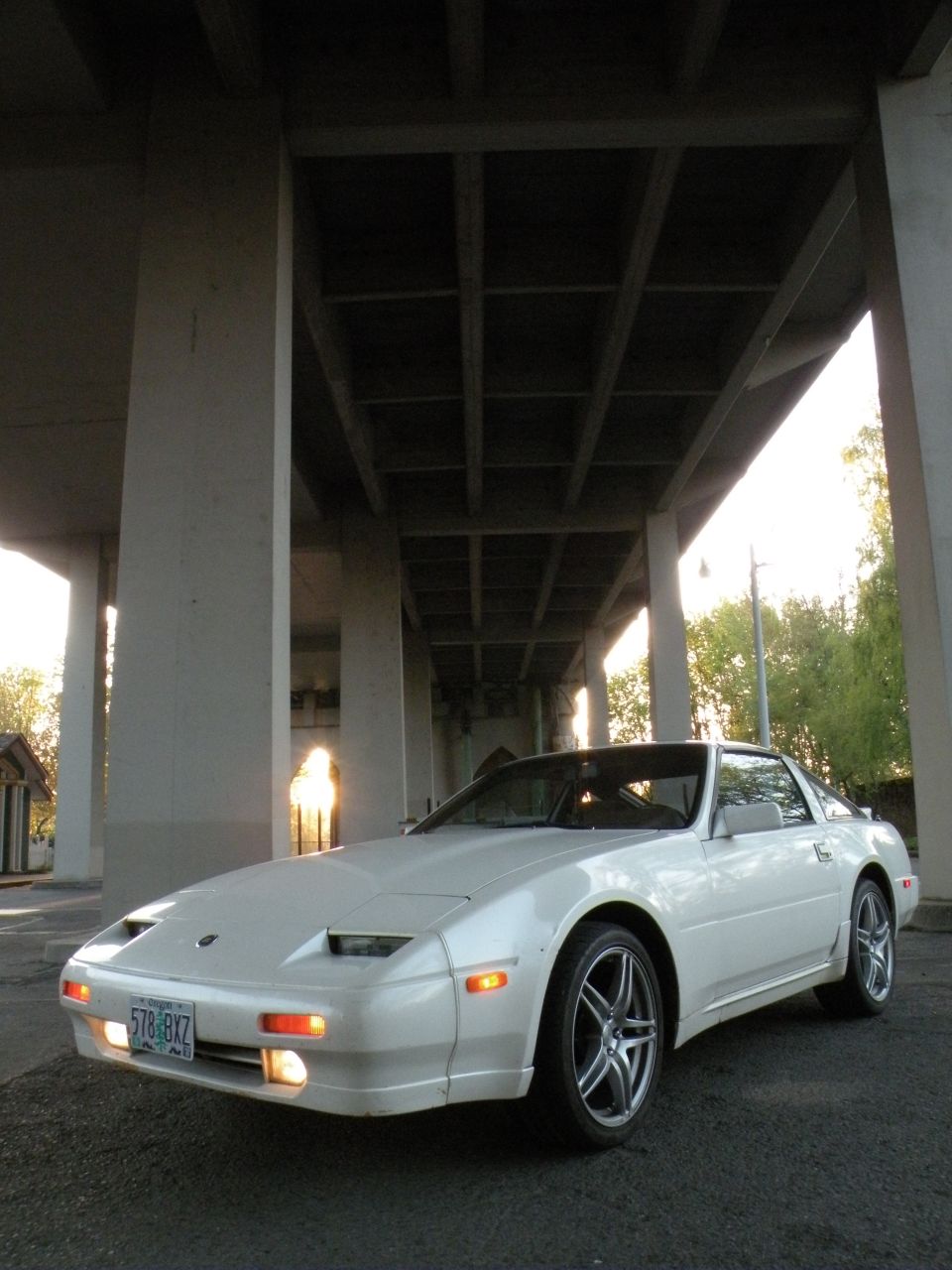 White 1989 Nissan 300ZX parked under a concrete overpass, front quarter view.
