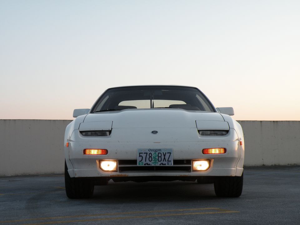 White 1989 Nissan 300ZX front view, headlights down, turn signals on.