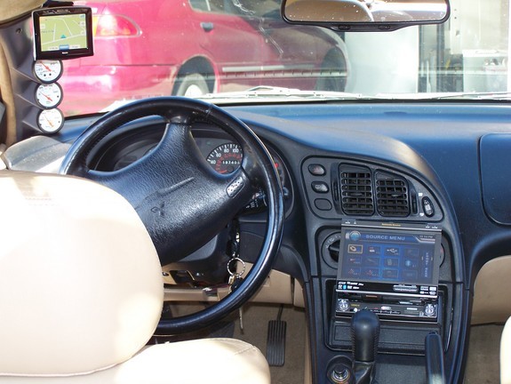 Car interior dashboard with GPS, gauges, steering wheel, and infotainment system.