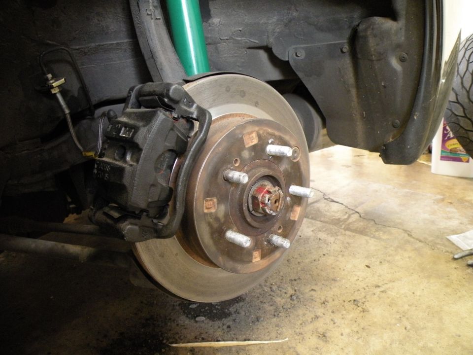 Close-up of a car's brake caliper and rotor assembly, with a green shock.