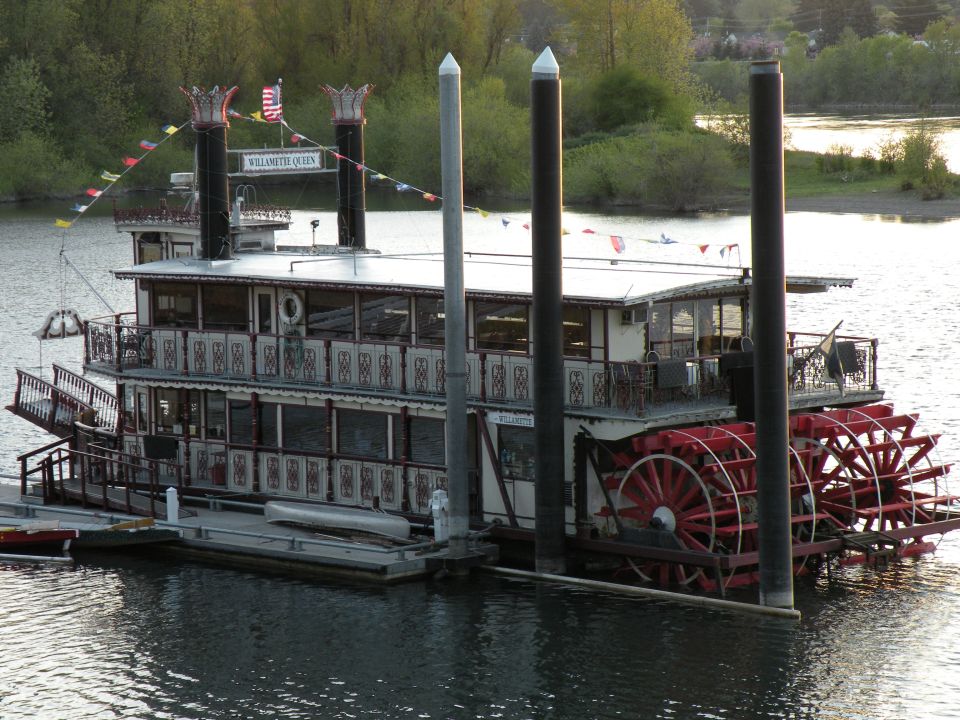The Willamette Queen paddlewheel riverboat docked on the water.