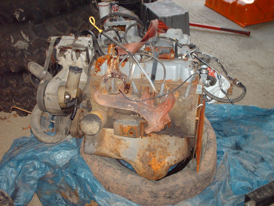 Rusty bare engine block with exhaust manifolds on a tarp