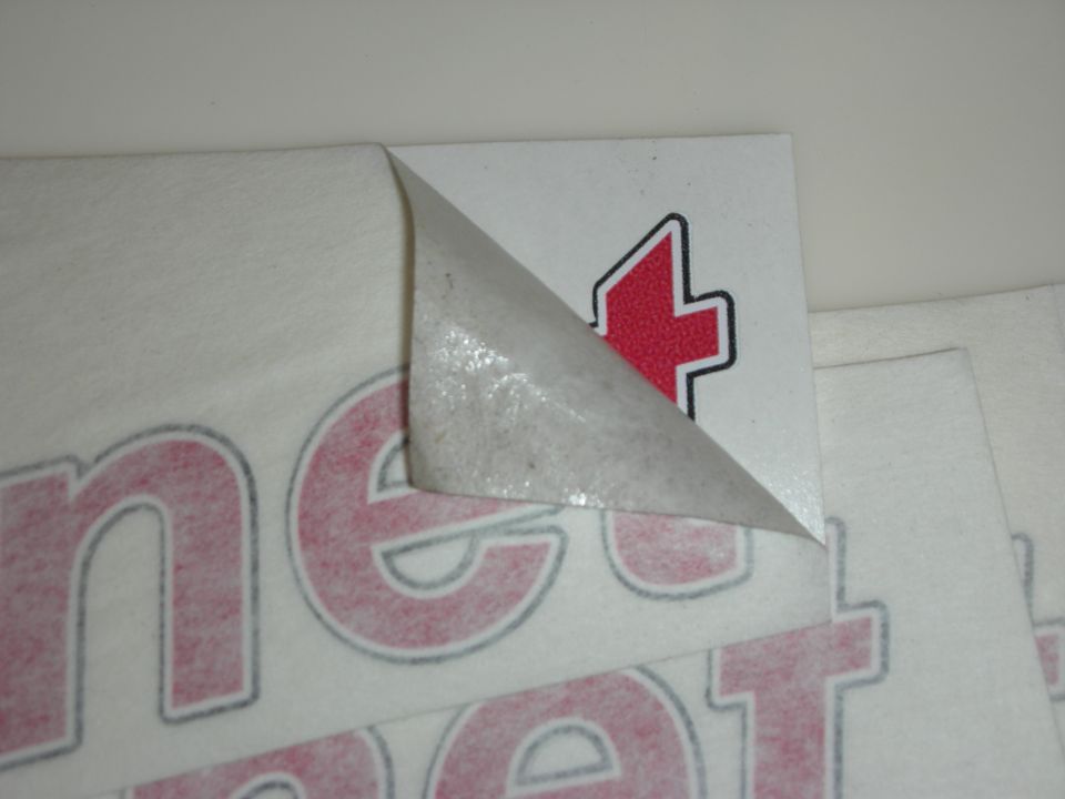 Vinyl decal sheets with a partially peeled backing on a white surface