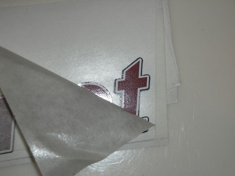 Vinyl decal sheet with backing peeled showing a red letter