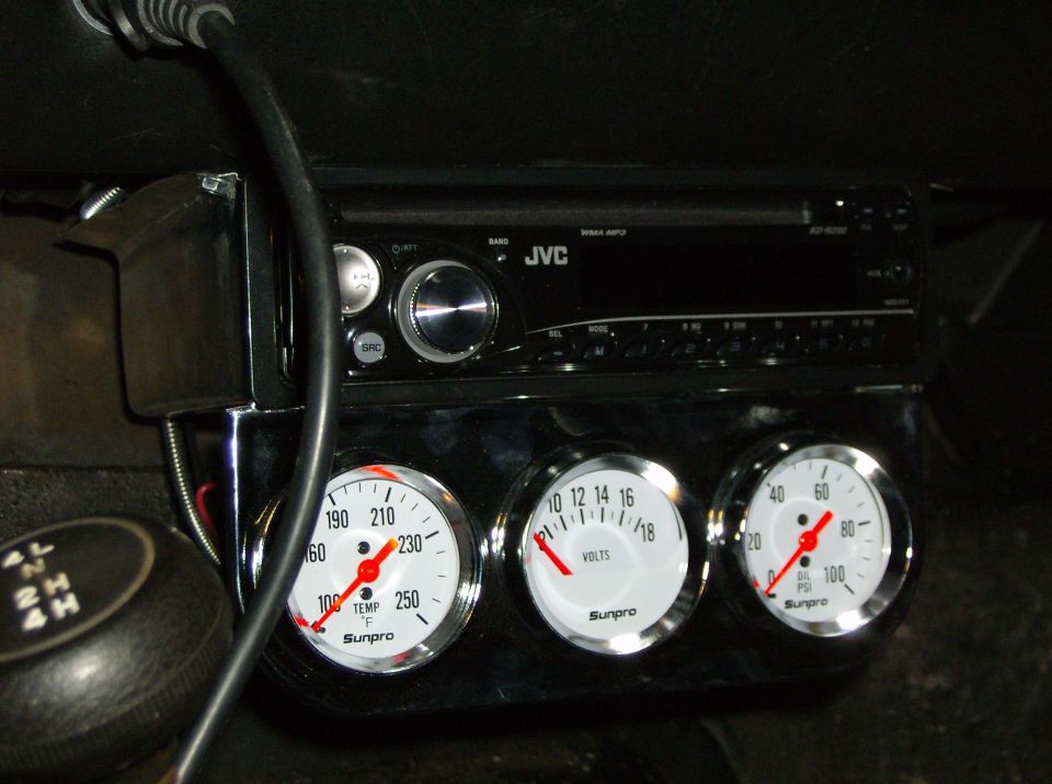 Vehicle dashboard with JVC stereo, temperature, voltage, and oil pressure gauges, and a manual shifter.
