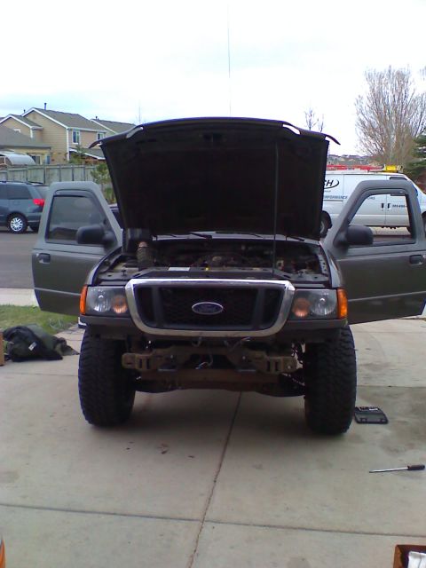 2004 Ford Ranger - A front-end view of a dark gray Ford Ranger pickup truck with the hood and driver's side door open. The front bumper appears to be removed,…