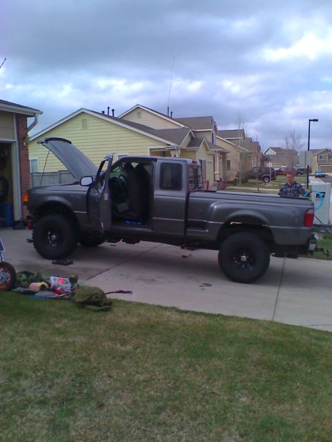 2004 Ford Ranger - A gray four-door Ford Ranger pickup truck is parked in a driveway with its hood and driver's door open. Various items are laid out on the g…