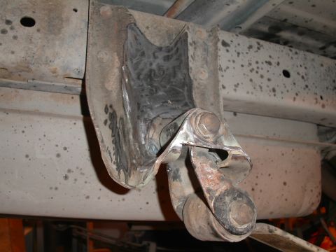 1990 Chevrolet Suburban - A close-up view of the rusted and modified rear suspension leaf spring mounting bracket on a Chevrolet Suburban. The bracket appears to hav…