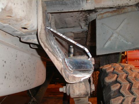 1990 Chevrolet Suburban - Close-up view of the underside of a vehicle, showing a custom-fabricated metal bracket welded to the frame near the rear tire. The bracket…