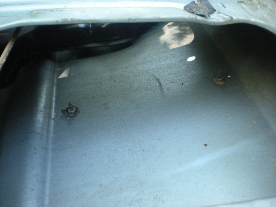 Close-up of interior vehicle body panel with two fasteners and rust.