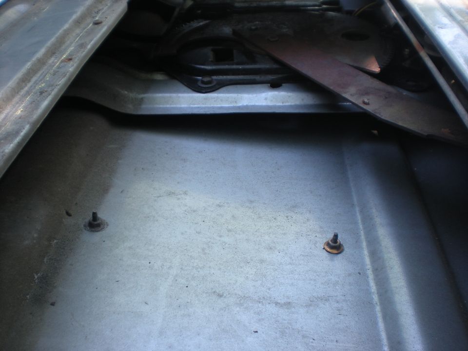 Interior of a vehicle door panel showing window regulator mechanism and two screws.
