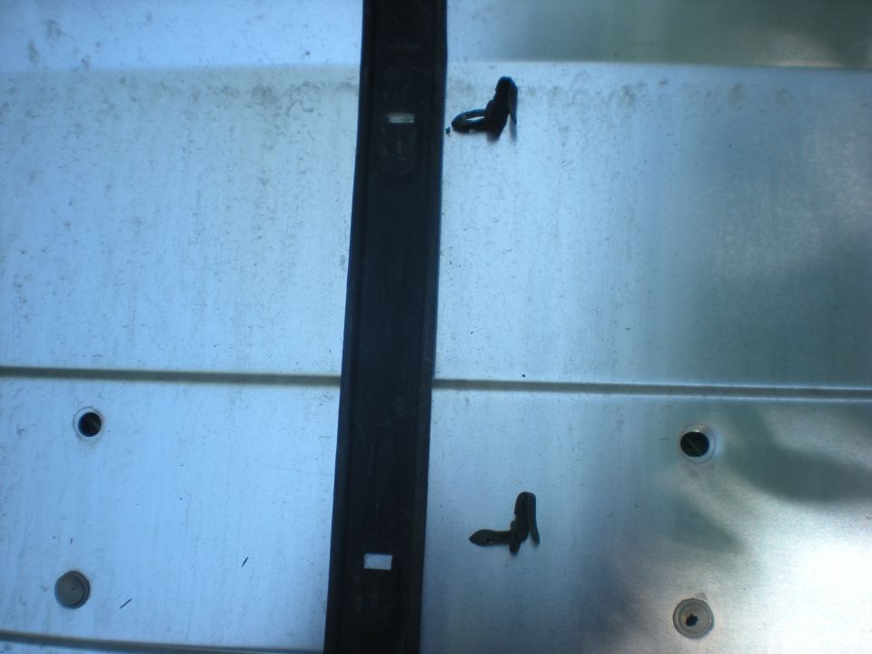 Interior of a 1990 Ford Bronco with a black trim piece and clips on a metallic panel.