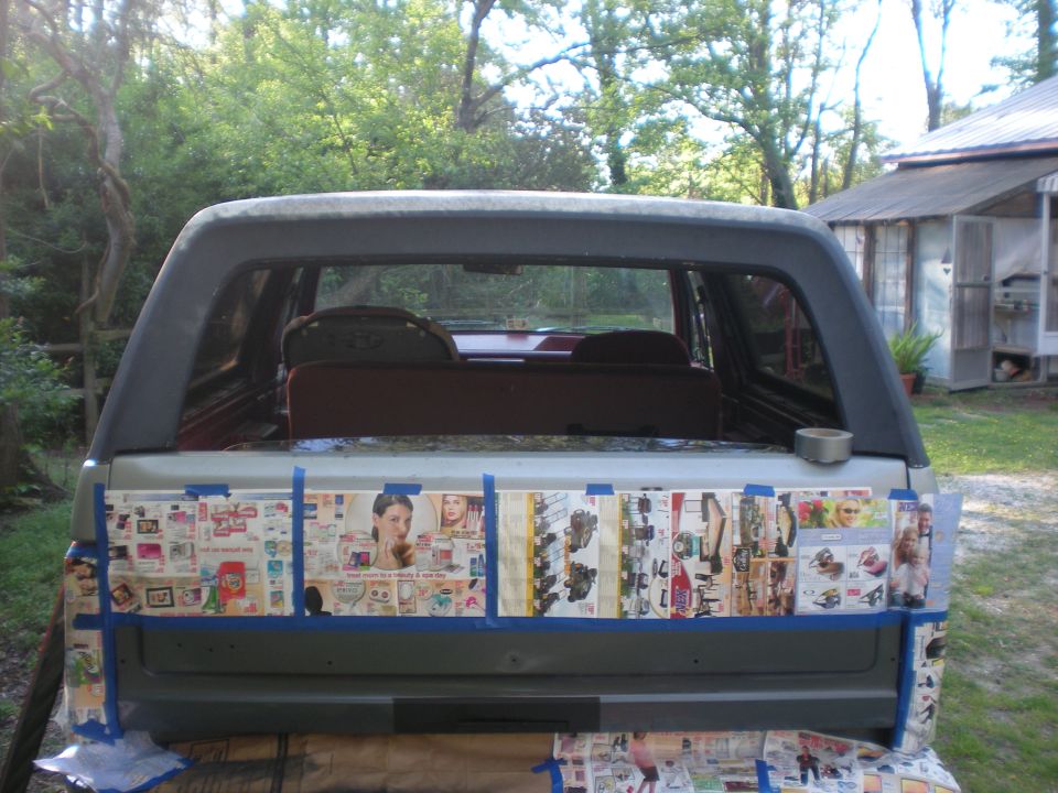 Rear view of a dark gray SUV tailgate covered in taped-on magazine clippings.