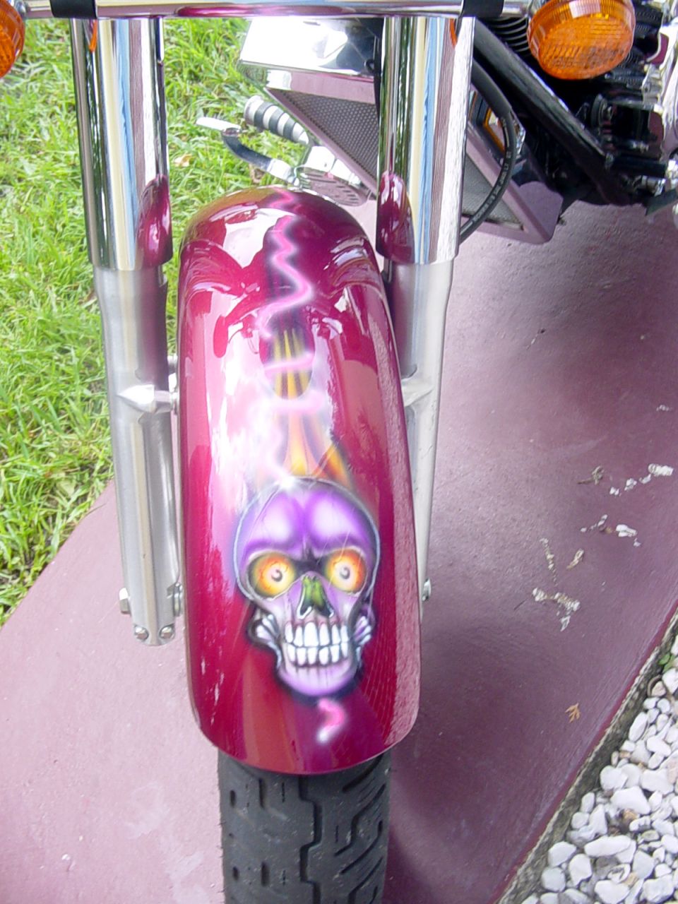 Motorcycle front fender in metallic red with airbrushed purple skull and chrome forks