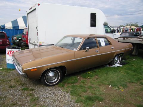 2001 Ford Crown Victoria - A gold 1959 Plymouth Fury is parked outdoors on a grassy area.