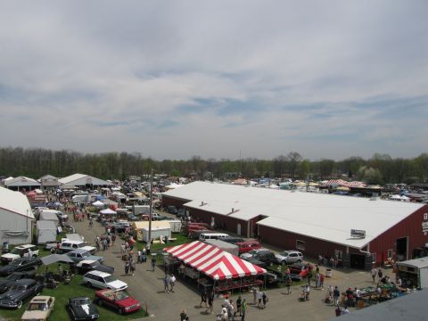 2001 Ford Crown Victoria - A wide view of an outdoor event numerous vehicles and vendor tents, suggesting a car show or swap meet.