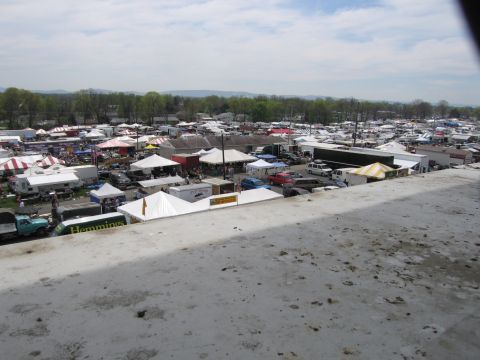 2001 Ford Crown Victoria - A wide view of an outdoor market filled with numerous tents and vehicles under a cloudy sky.