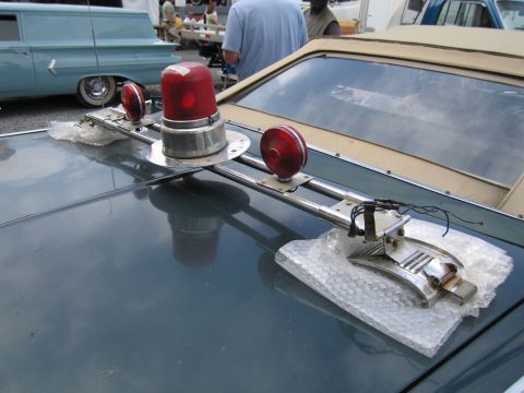 2001 Ford Crown Victoria - A close-up of a car's roof shows a light bar with red lights and siren components, with another vehicle visible in the background.
