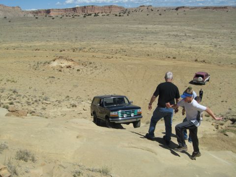 1993 Ford Bronco - A 1993 Ford Bronco navigates a desert landscape, with people observing and another vehicle in the distance.