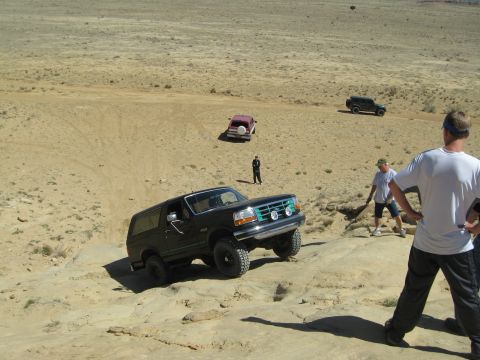 1993 Ford Bronco - A black Ford Bronco navigates a challenging off-road course with other vehicles in the background.
