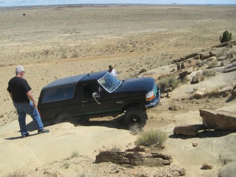 1993 Ford Bronco - 1993 Ford Bronco tackling challenging off-road terrain in a desert landscape.