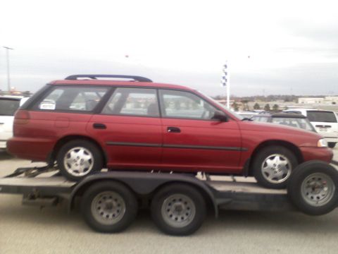 1998 Subaru Legacy - A red station wagon is transported on a trailer, showing its side profile and roof rack.