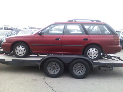 1998 Subaru Legacy - A red station wagon is transported on a trailer, showing its side profile and roof rack.