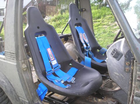 1987 Suzuki Samurai - The interior of an off-road vehicle features two black racing seats equipped with blue RJS racing harnesses.