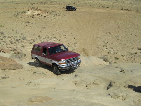 1993 Ford Bronco - A red and silver 1993 Ford Bronco navigates a rocky, off-road trail with another vehicle in the background.