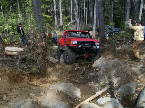 1989 Ford Bronco - Modified 1989 Ford Bronco tackling a challenging rocky obstacle on an off-road trail.