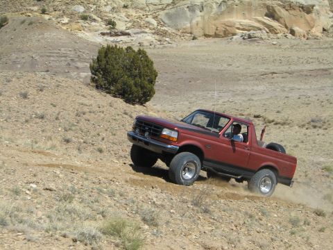 1993 Ford Bronco - This 1993 Ford Bronco navigates a challenging off-road terrain with a dusty trail behind it.