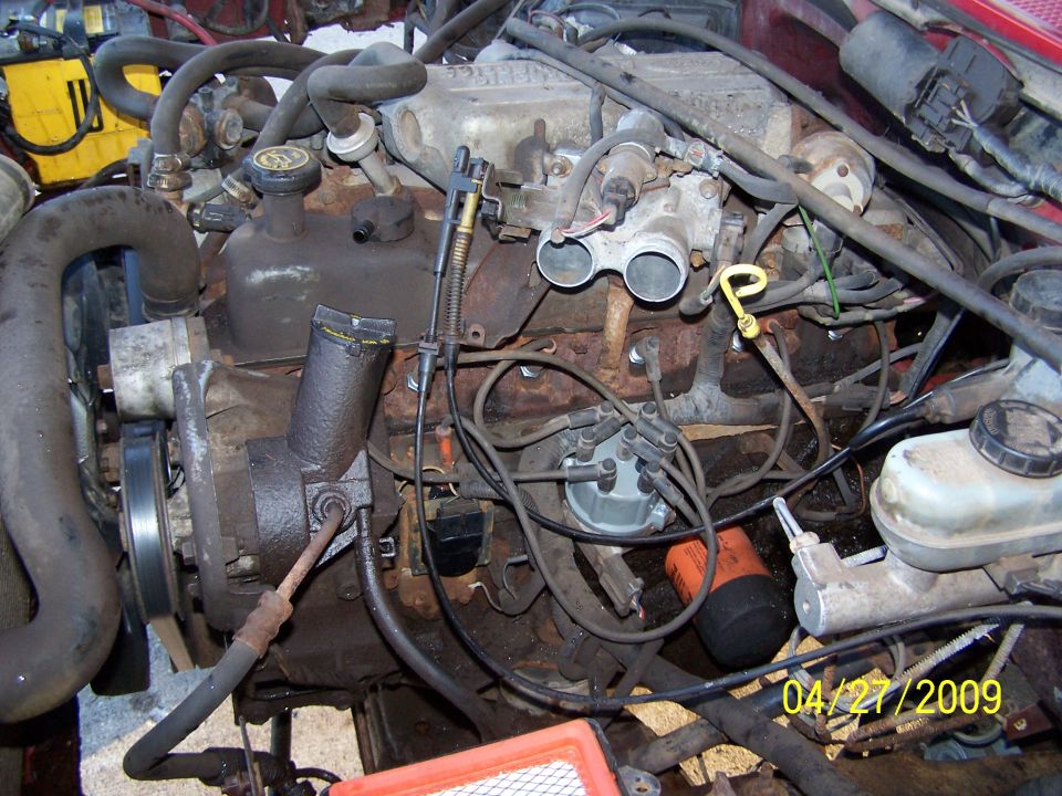Engine bay with hoses, wires, distributor, and oil filter visible. Date stamp reads 04/27/2009
