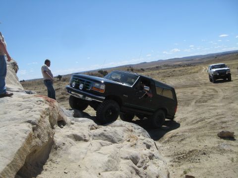1993 Ford Bronco - A black 1993 Ford Bronco tackles a challenging off-road course with another vehicle visible in the background.