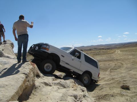 1993 Ford Bronco - A white 1992 Ford Bronco navigates a challenging rocky terrain under a clear blue sky.
