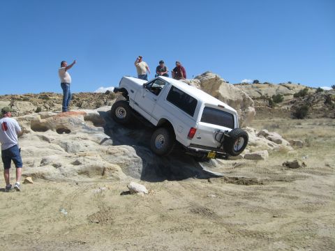 1993 Ford Bronco - A white 1993 Ford Bronco navigates a challenging rocky incline with several onlookers.