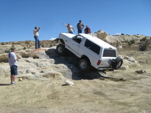 1993 Ford Bronco - White 1993 Ford Bronco navigating a rocky off-road trail with several onlookers.