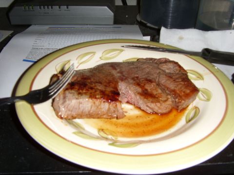 1978 Ford Bronco - A close-up of a cooked steak on a decorative plate, with a fork and knife ready for eating.