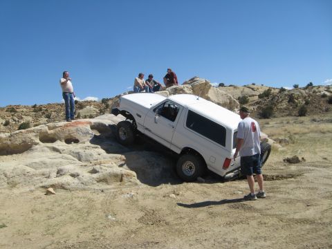 1993 Ford Bronco - A white 1993 Ford Bronco tackles a challenging off-road course with spectators watching.