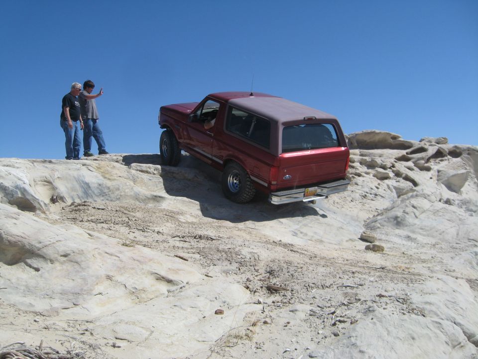 Red 1993 Ford Bronco off-roading on rocks