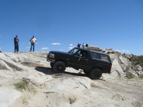 1993 Ford Bronco - A black 1992 Ford Bronco navigates a challenging off-road course on a sunny day.