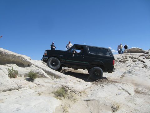 1993 Ford Bronco - This black 1993 Ford Bronco is shown tackling a challenging off-road course with steep inclines and rocky obstacles.