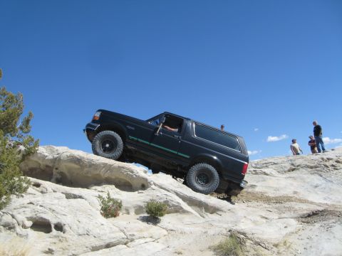 1993 Ford Bronco - 1993 Ford Bronco navigating challenging off-road terrain on a sunny day.