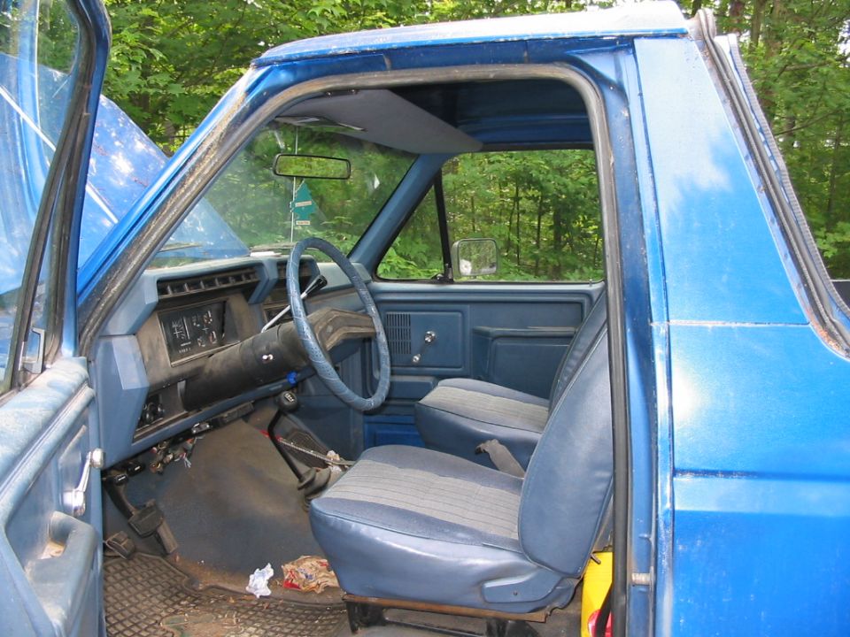 Blue Ford Bronco interior with cloth seats, dashboard, steering wheel, and open driver's door