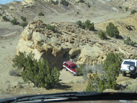 1993 Ford Bronco - Two SUVs, including a 1993 Ford Bronco, traverse a desert terrain with rocky formations.