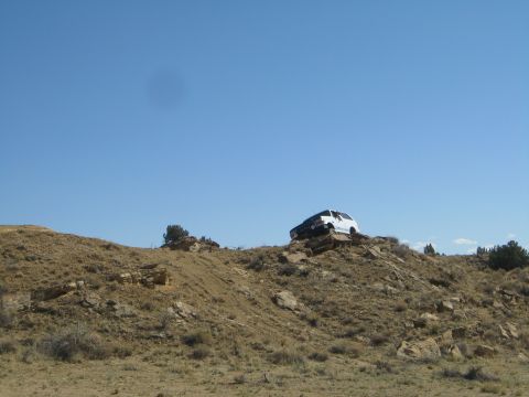 1993 Ford Bronco - A white SUV navigates a rocky, arid landscape under a bright blue sky.