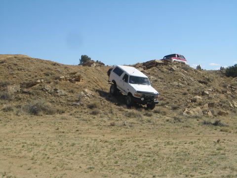 1993 Ford Bronco - Two SUVs navigate a rocky, off-road terrain under a clear blue sky.