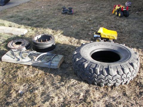 1990 Chevrolet Suburban - Various toy vehicles and tire components are scattered across a grassy area.
